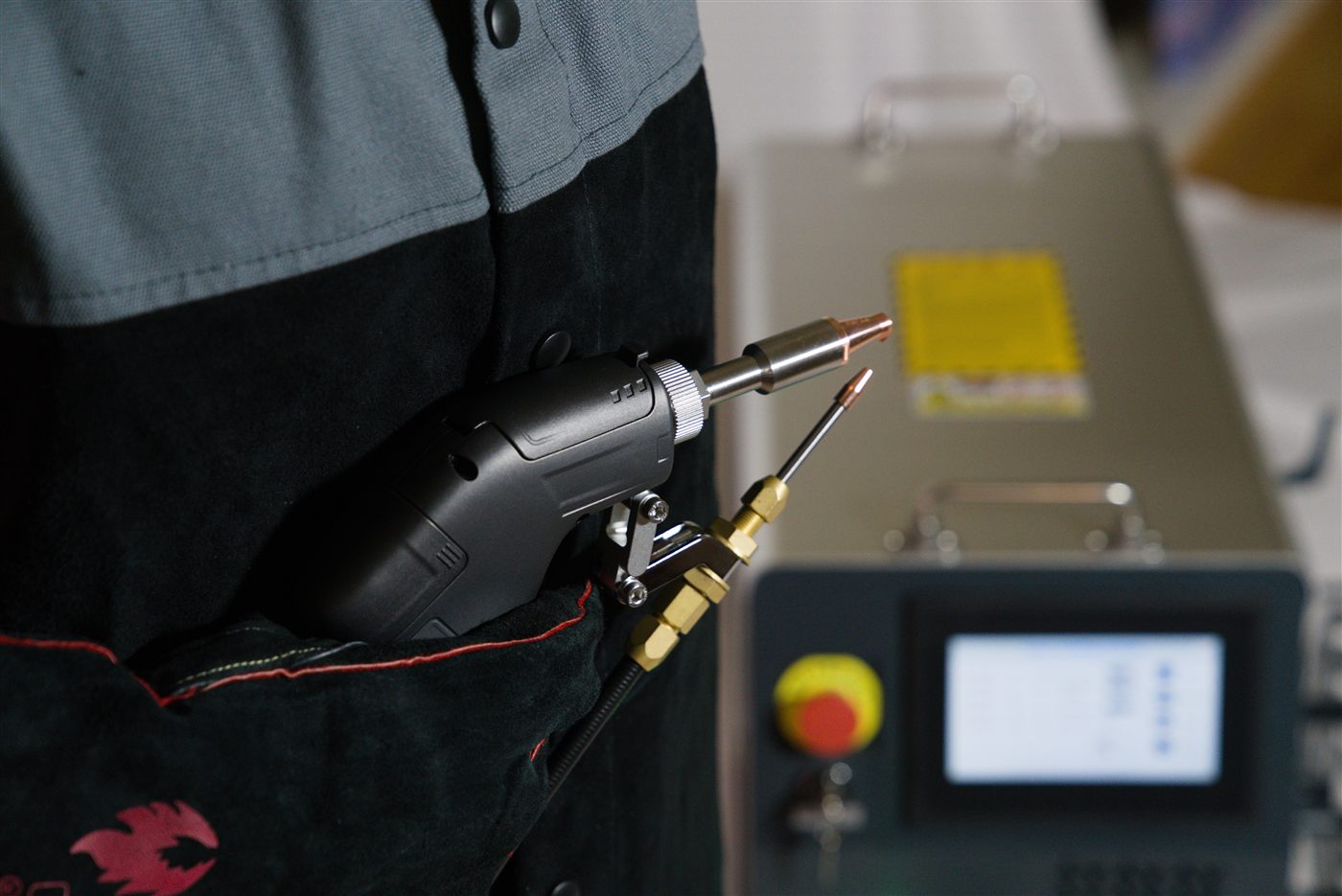 NX-1500 Air welding gun holstered at the operator's hip, with the touchscreen and e-stop in the background