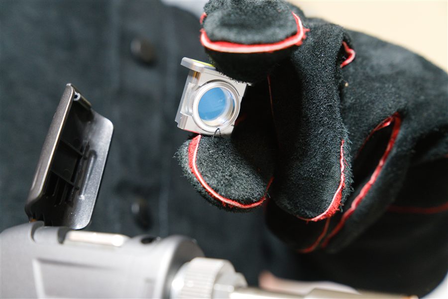 Protective lens cartridge held between gloved fingers
