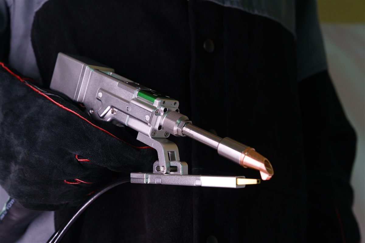 Liquid-cooled NX-Series welding torch fitted with the optional dual wire feeder, held in a gloved hand